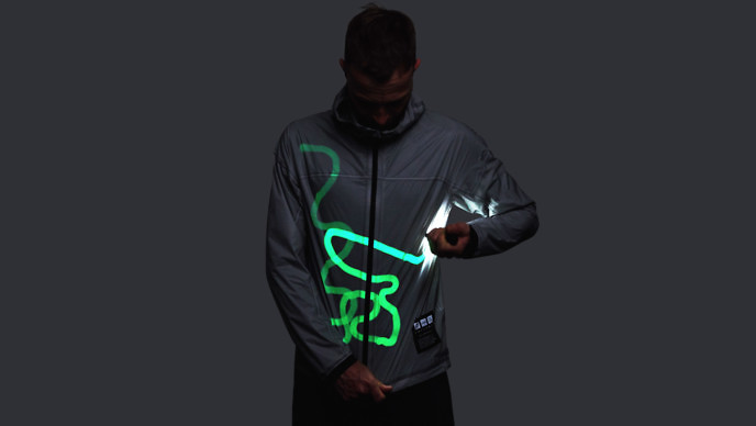 Man drawing bright green lines on a gray jacket with a hand-held light