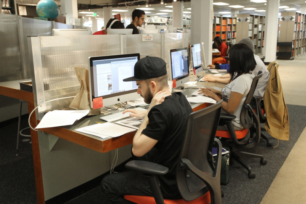 Students looking up financial aid information in a library